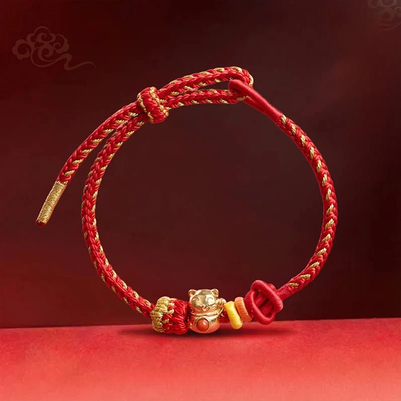 Close up of secure braided knot of copper cat red string luck bracelet on red gradient background