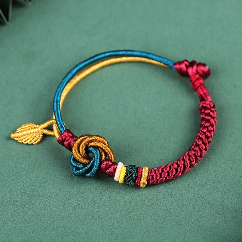 Handwoven rope bracelet side view showing twisted wine red band with blue gold edge and knot
