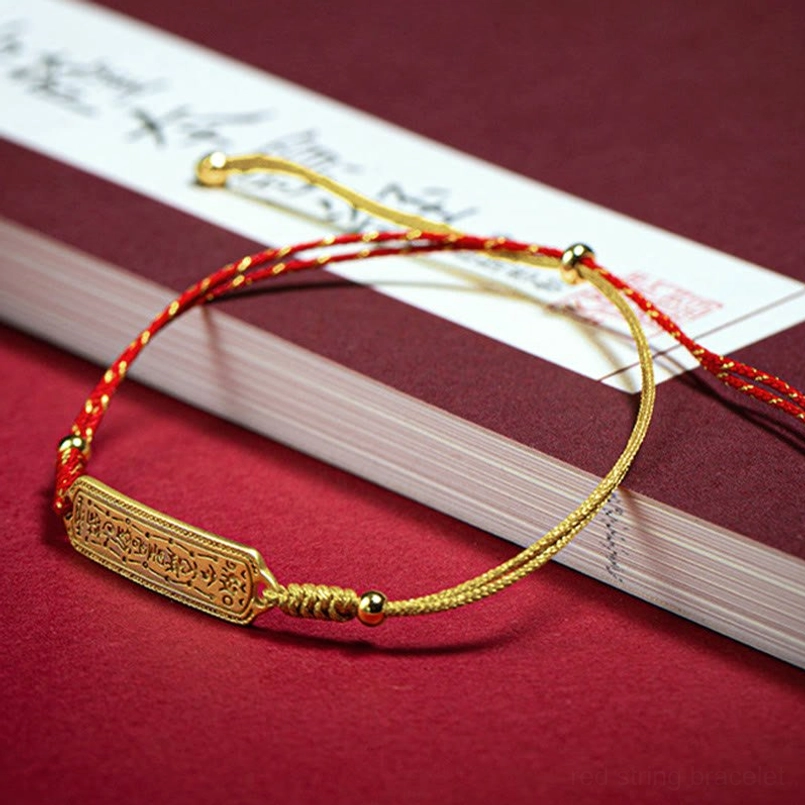Braided red gold amulet bracelet overhead view placed on calligraphy book