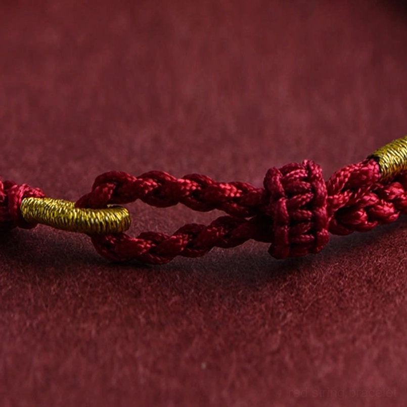 Red string bracelet gold ring charm smooth woven rope texture close-up