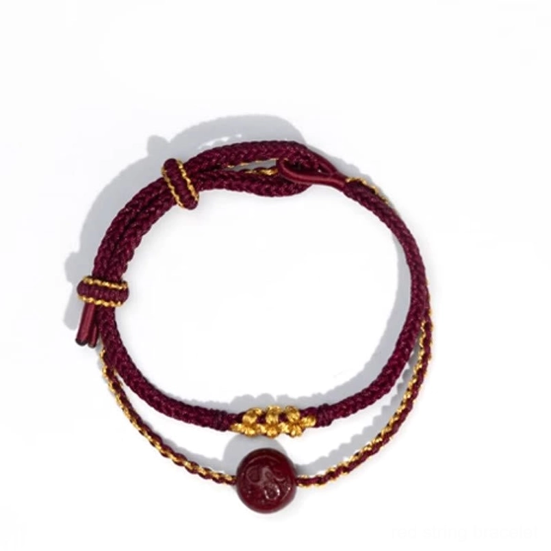 Top-down view of eight-strand braided red string bracelet with adjustable pull knot and gold accents