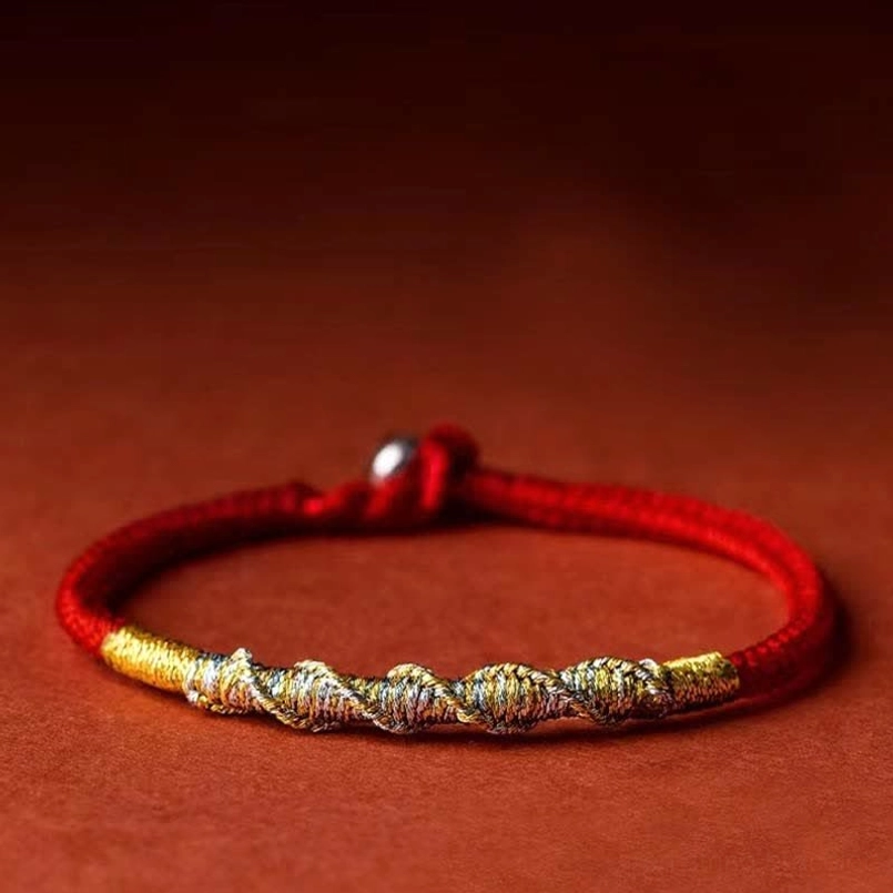 Red-gold braided protection bracelet flat lay showing push metal clasp and twisted design