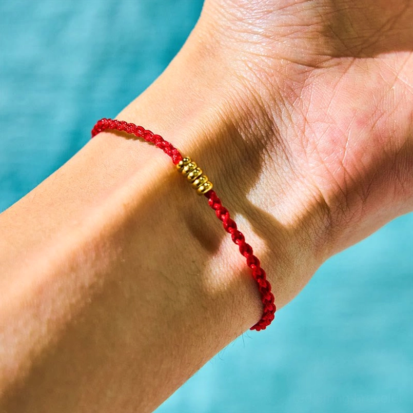 Bright red braided cord bracelet with metal beads display