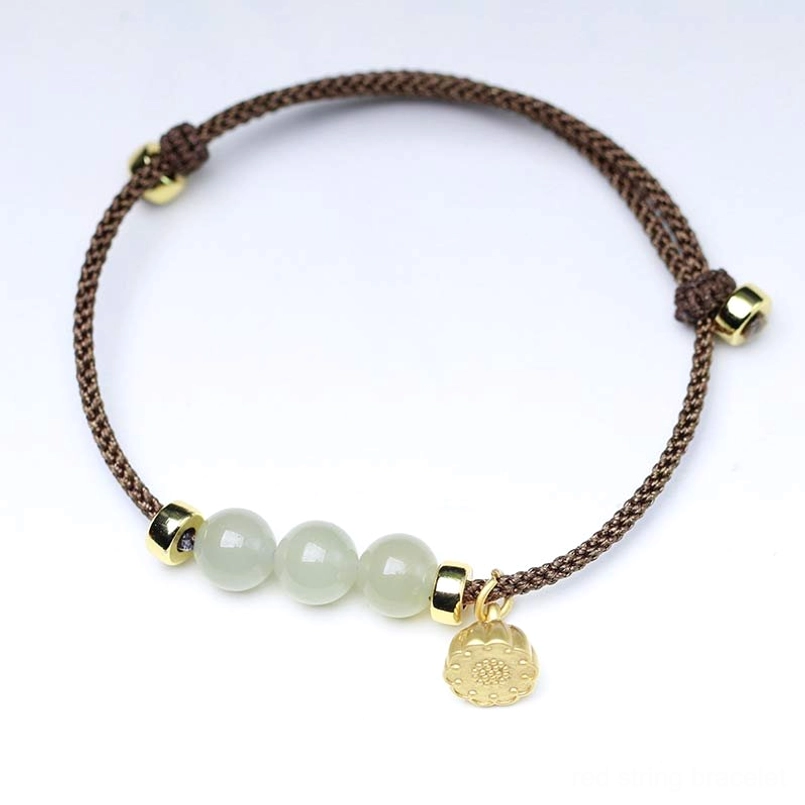Brown woven jade bracelet with gold round medallion charm and adjustable slider on white background