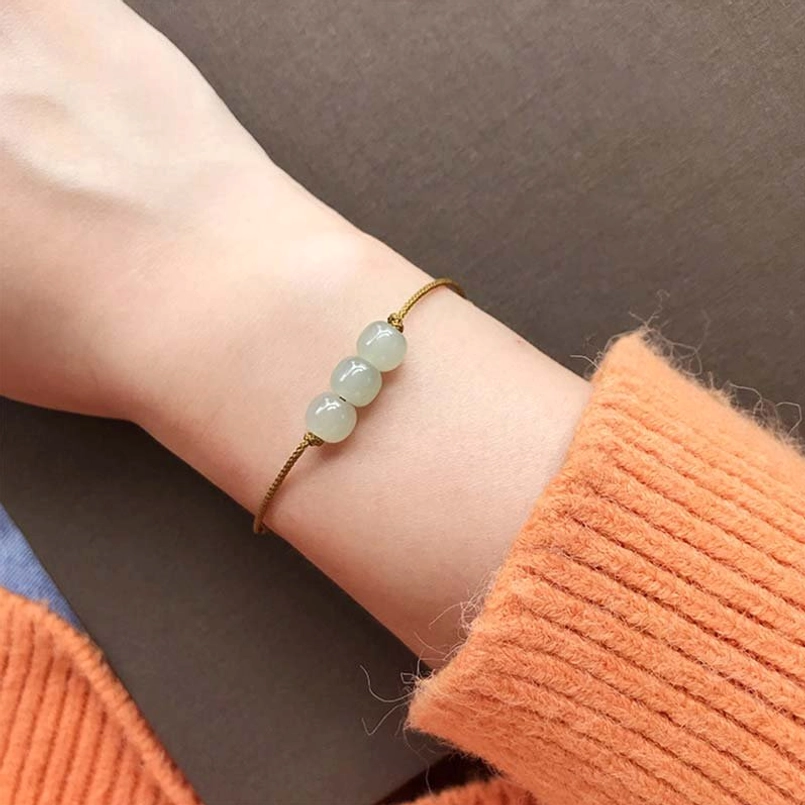 Brown cord jade bracelet worn on wrist with orange knit - comfortable adjustable fit