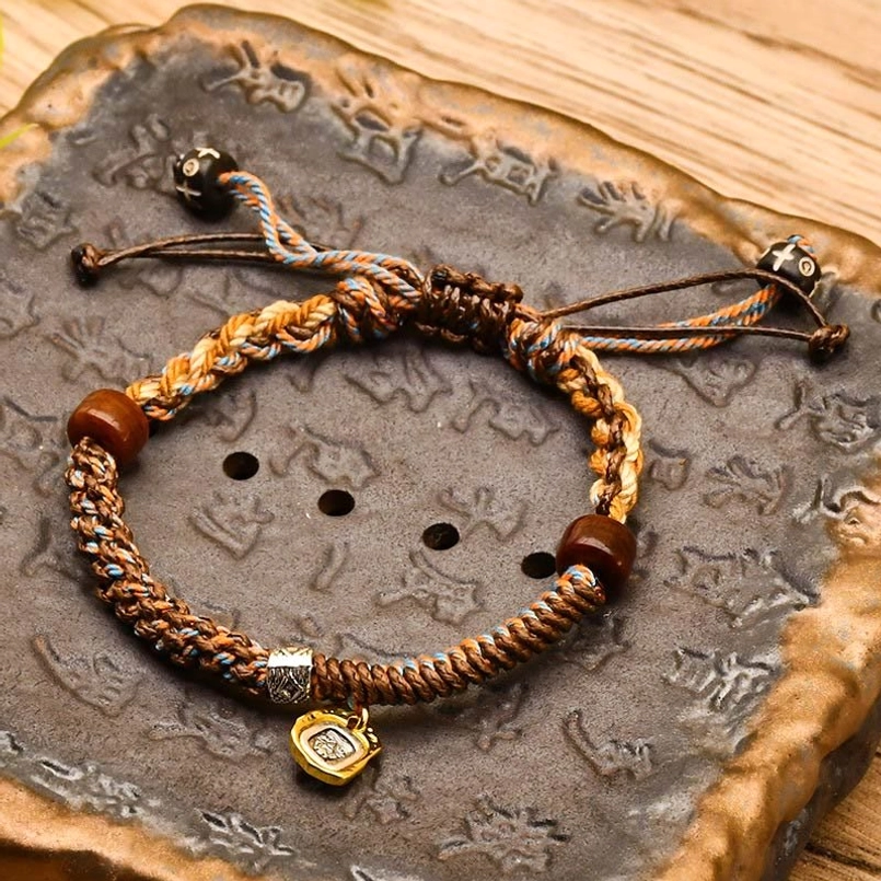 Brown Tibetan braided Zakiram goddess of wealth bracelet on carved vintage stone tray