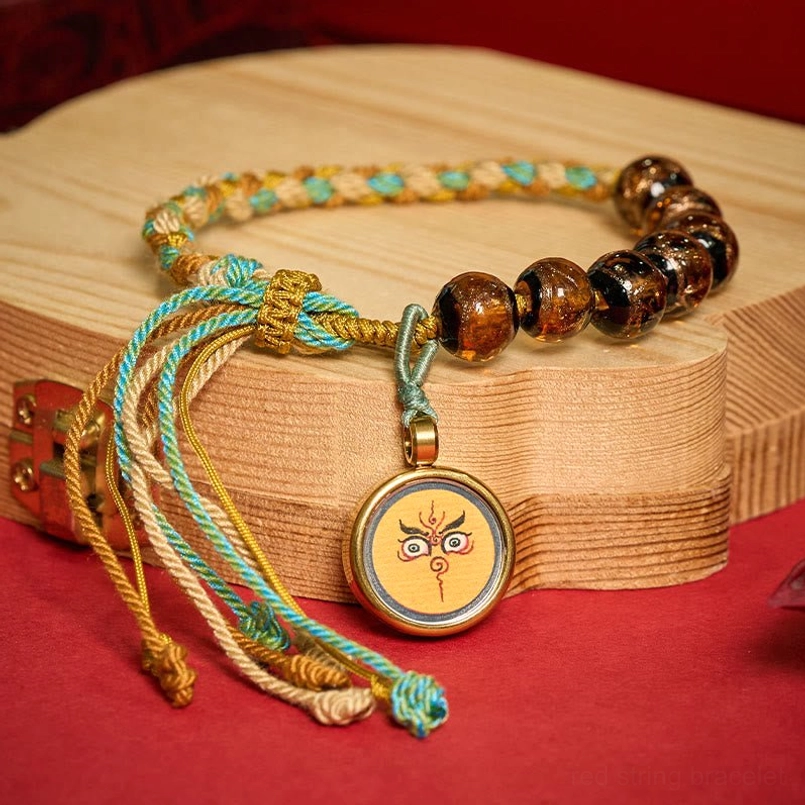 Tibetan liuli glass bead bracelet Buddha eye charm detail on neutral background