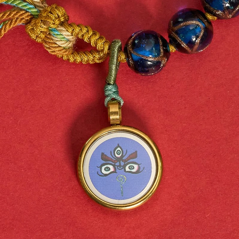 Tibetan Buddha eye bracelet pendant and knot detail with green and purple liuli glass beads