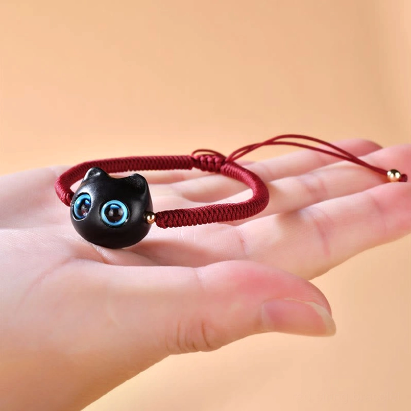 Cat charm bracelet placed on human palm showing adjustable knot design