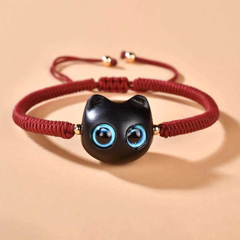 Side view of cat head bracelet showing woven cord and ebony wood charm detail