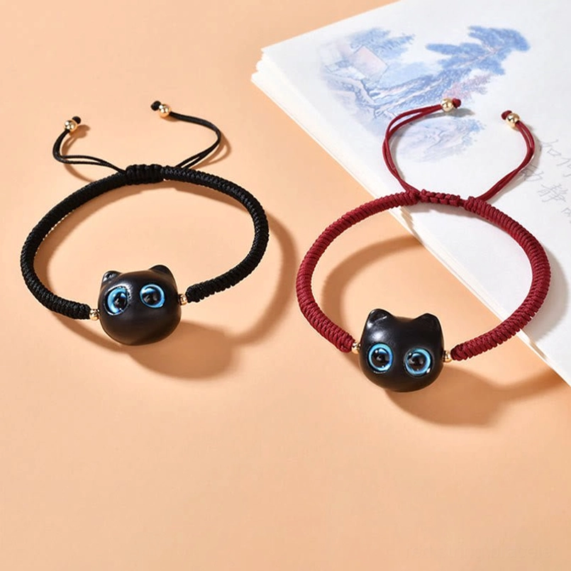 Two cat charm bracelets in black and wine red cord options displayed together