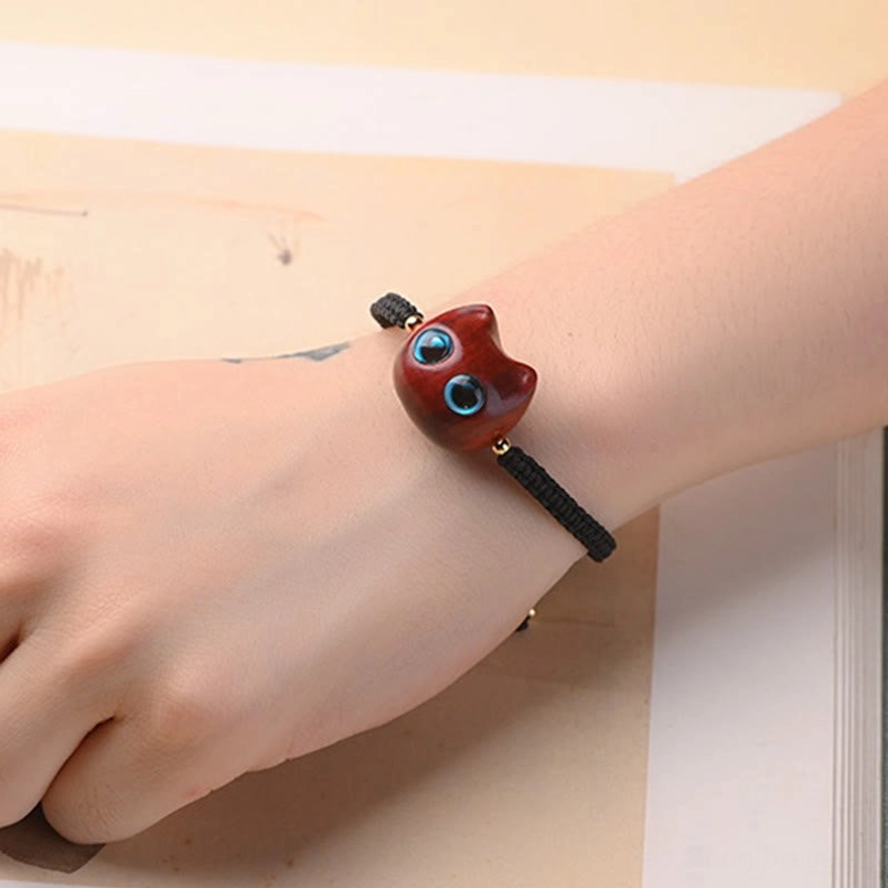 Cat head bracelet worn on wrist showing dark red sandalwood charm