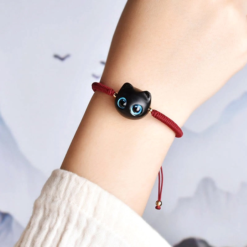 Ebony wood cat bracelet worn on human wrist in natural outdoor setting