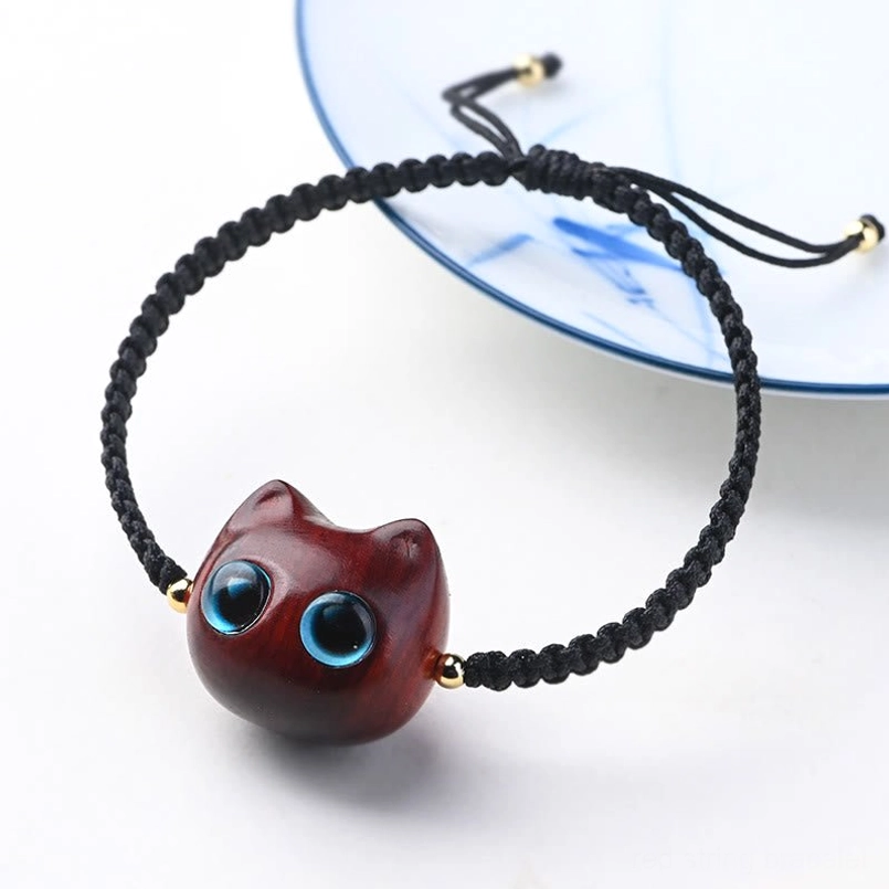 Lucky cat head red sandalwood ebony wood bracelet flat lay on blue ceramic plate
