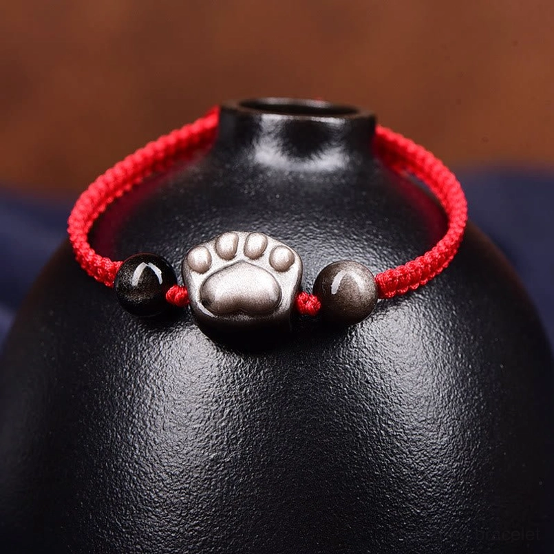 Close-up cat paw obsidian red string bracelet charm detail side view