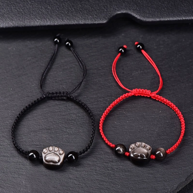 Pair of cat paw obsidian bracelets black and red rope options flat lay