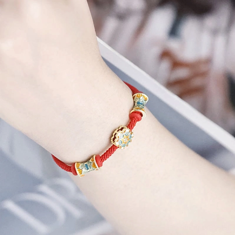 Close up of central floral bead and paired drum beads on Dunhuang red string bracelet