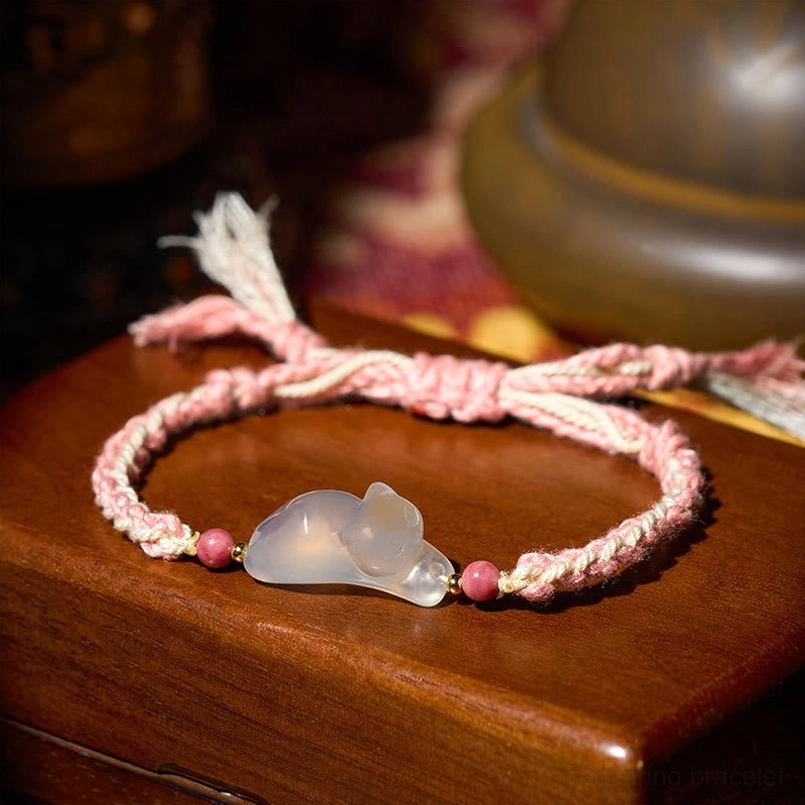 Three-quarter side view of pink and white woven chalcedony cat bracelet with matte finish pendant