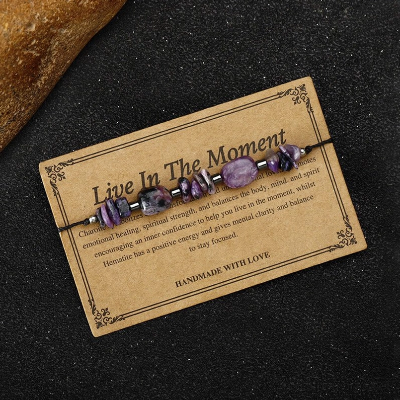 Live in the Moment healing bracelet on dark fabric showing red string and stone details
