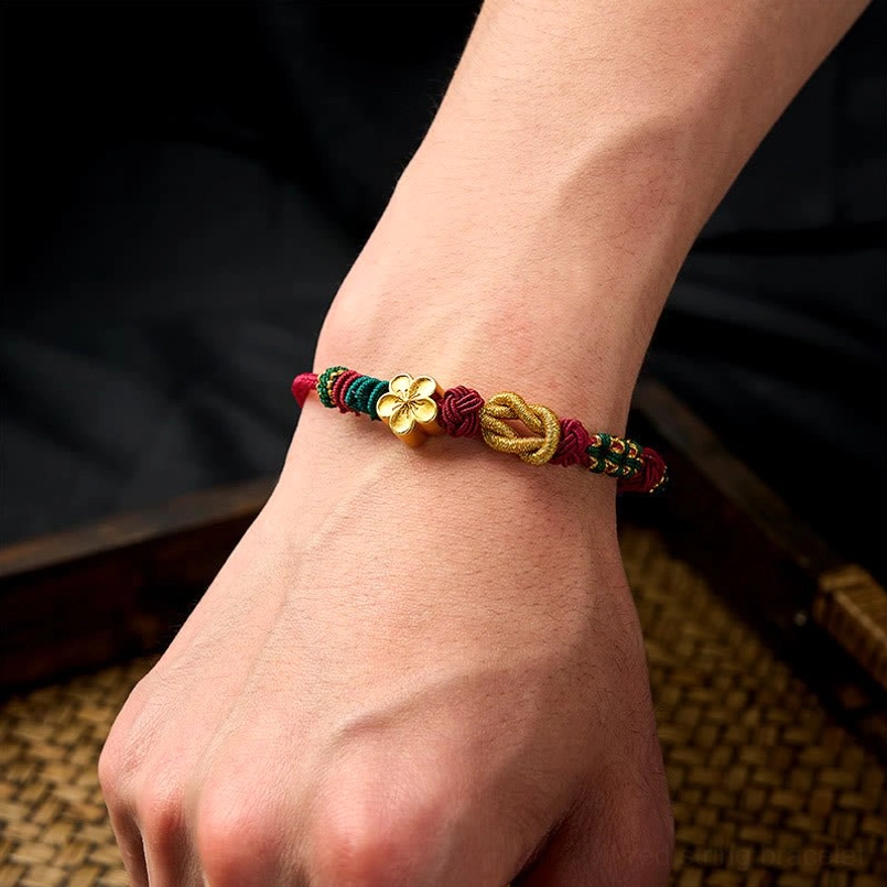 Hand-woven luck bracelet worn on wrist with gold four-leaf charm and multicolor braids