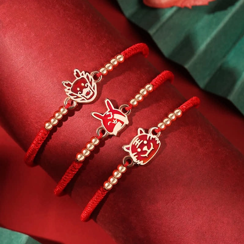 Collection of three Chinese Zodiac red string bracelets with enamel animal charms displayed flat lay