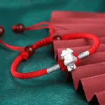 Chinese zodiac 999 sterling silver red string bracelet with silver ox charm and red agate beads, flat lay display