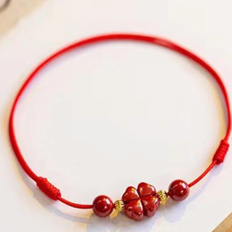 Cinnabar four leaf clover anklet with gold spacer beads and red woven rope flat display
