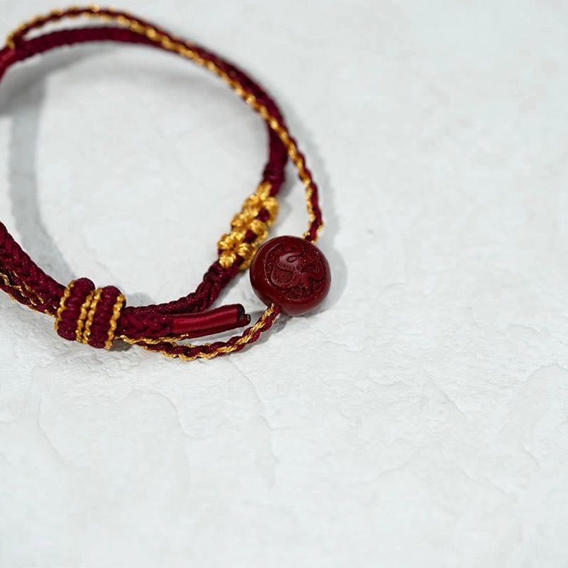 Detailed view of eight-strand braided texture with carved cinnabar bead and gold thread accents