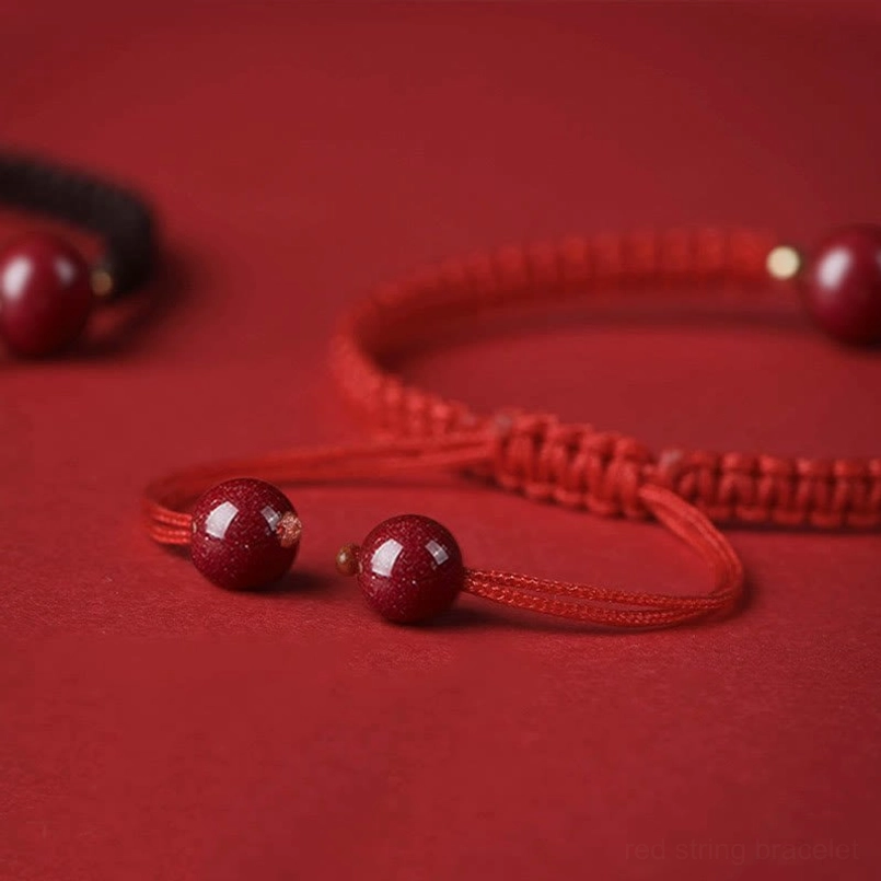 Cinnabar beads and red braided string components on red fabric backdrop