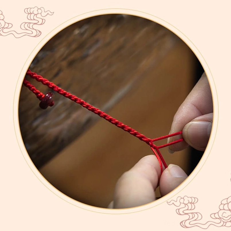 Cinnabar belly chain detail shot with braided rope and adjustable knot on wooden backdrop with Chinese cloud frame