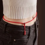 Cinnabar red string belly chain worn on waist in casual daily outfit, showing braided rope design with cinnabar stone fastener