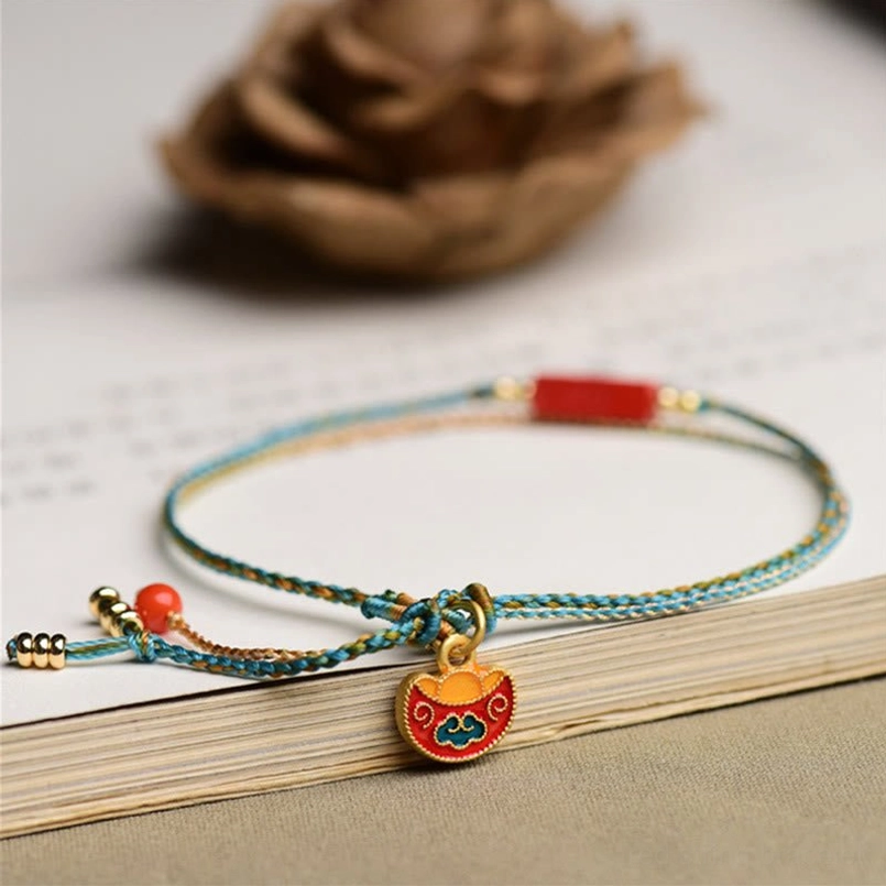 Oblique side view of double-layer cinnabar blessing bracelet with blue-yellow rope, lock charm, and red bead tassel
