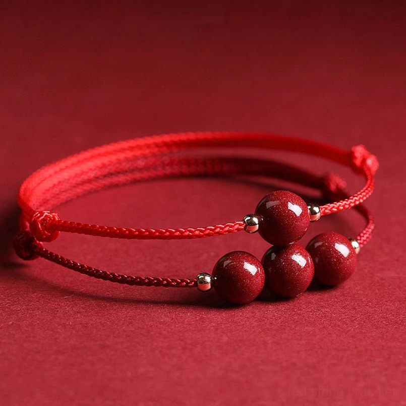 Multiple cinnabar bead red string bracelets with dual braided cords top view on solid red background