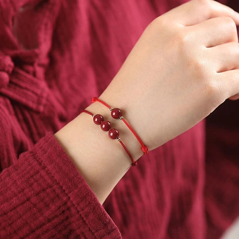 Dual cinnabar bead red string bracelets worn on woman's wrist with red clothing