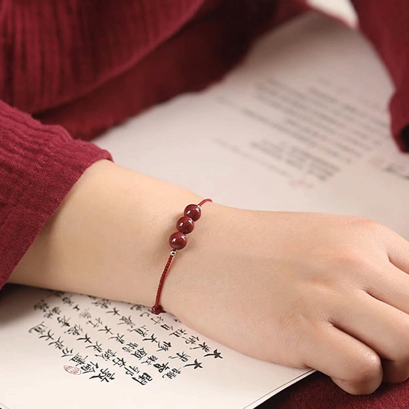 Red string cinnabar bracelet worn with matching anklet layered styling