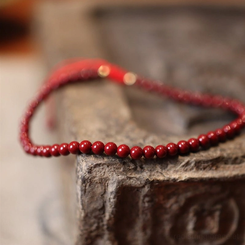 Natural cinnabar beaded bracelet on vintage stone surface with metal fastener detail