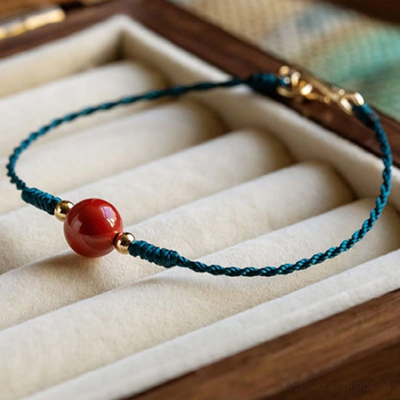 Close up view of cinnabar woven bracelet with red bead and gold spacer beads