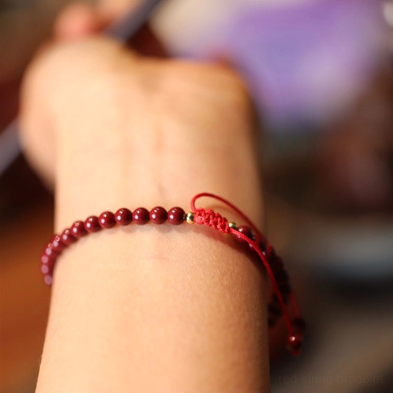 Cinnabar beaded bracelet with adjustable red woven cord tail and smooth red beads