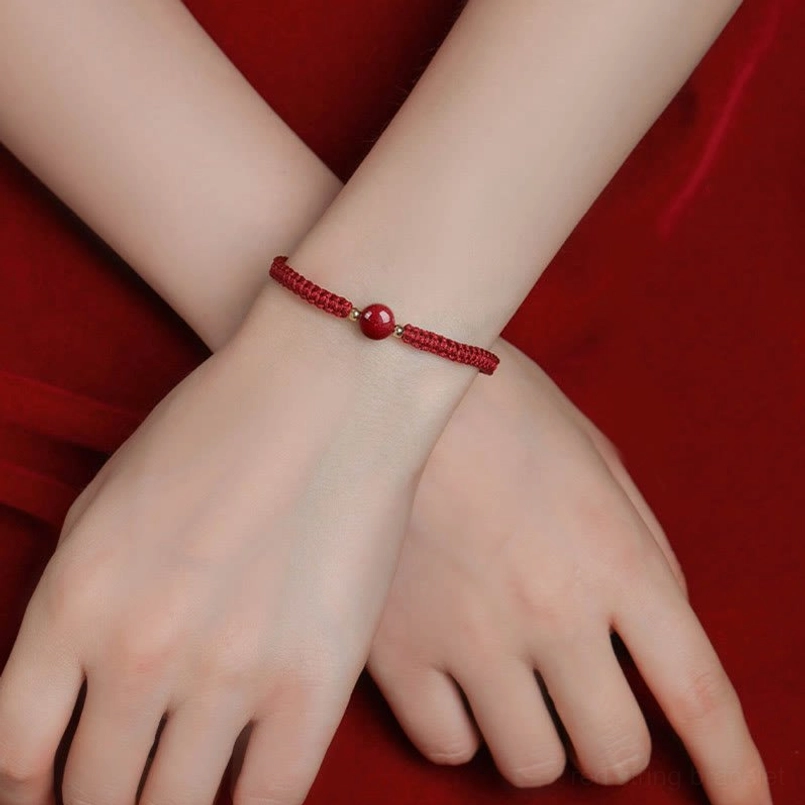 Dual wrist close-up with matching cinnabar red string bracelets showing minimal design