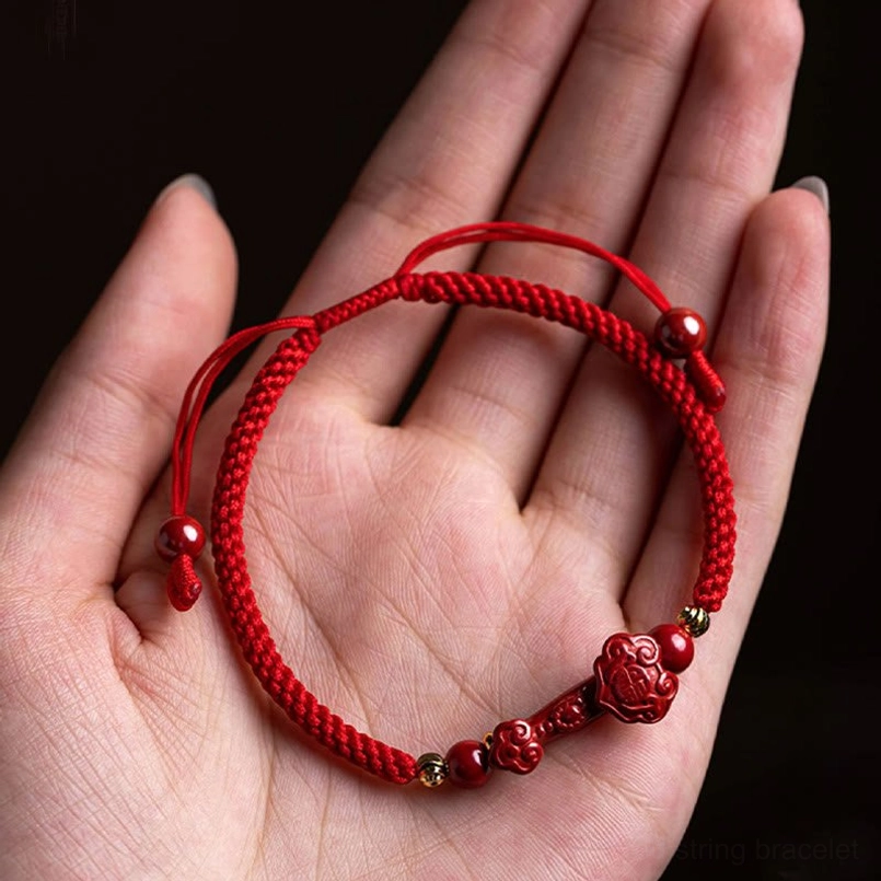 Cinnabar red string bracelet held in palm showing Ruyi charm detail
