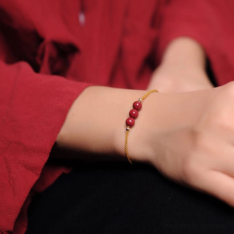 Cinnabar red string bracelet worn on wrist with yellow cord red clothing