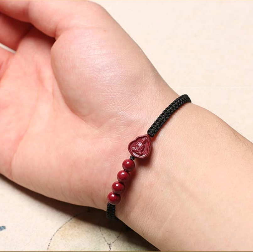 Black braided cord cinnabar Buddha bracelet worn on wrist lifestyle shot