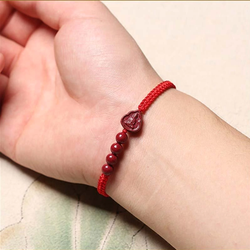 Red string cinnabar Buddha bracelet worn on wrist side view