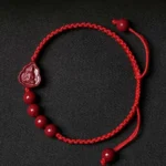 Cinnabar Buddha red string bracelet flat lay with braided cord and pendant beads