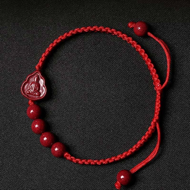 Cinnabar Buddha red string bracelet flat lay with braided cord and pendant beads