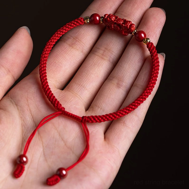 Red string bracelet with carved cinnabar charm and adjustable fit