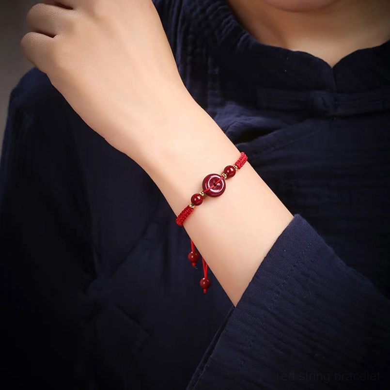 Minimalist red cord cinnabar coin charm bracelet on wrist
