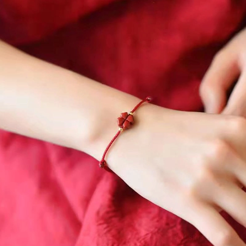 Cinnabar four leaf clover red string bracelet worn on human wrist close-up detail view