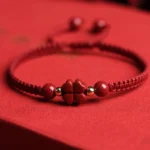 Four-leaf clover cinnabar red string bracelet with gold spacers on red background