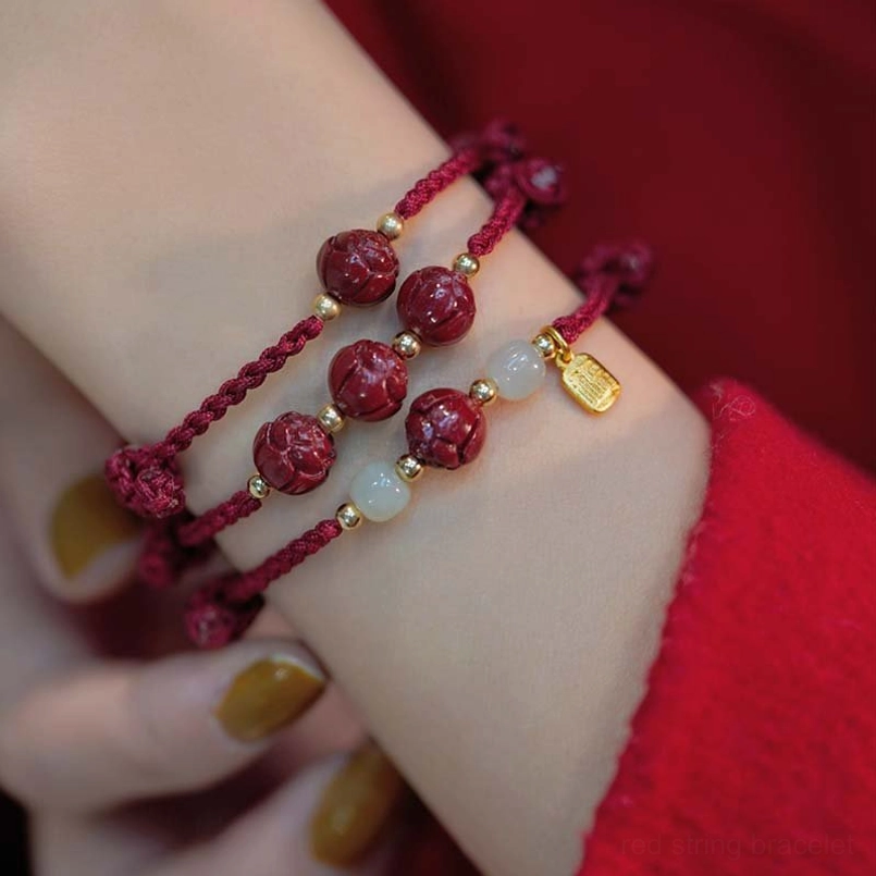 Multiple handmade cinnabar bracelets stacked on wrist with gold pendants and jade accents
